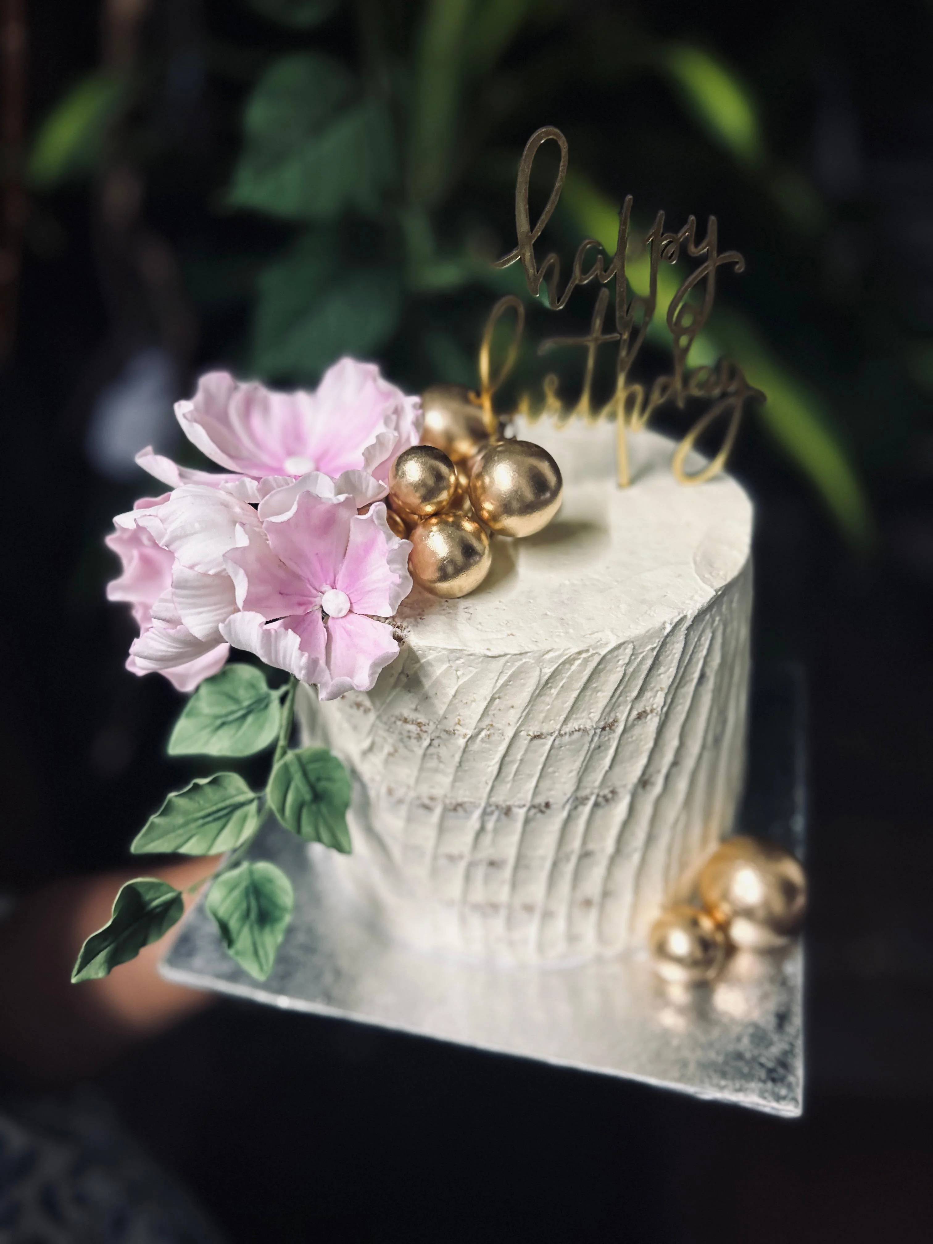 Fête — textured buttercream celebration cake with hand-crafted pink sugar flowers and gilded chocolate spheres